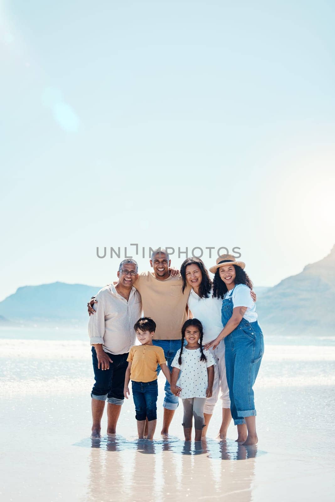 Family, beach portrait and smile on vacation, bonding and love in summer sunshine by mock up space. Group, men and women with children with happiness, freedom and adventure by sea waves on holiday by YuriArcurs