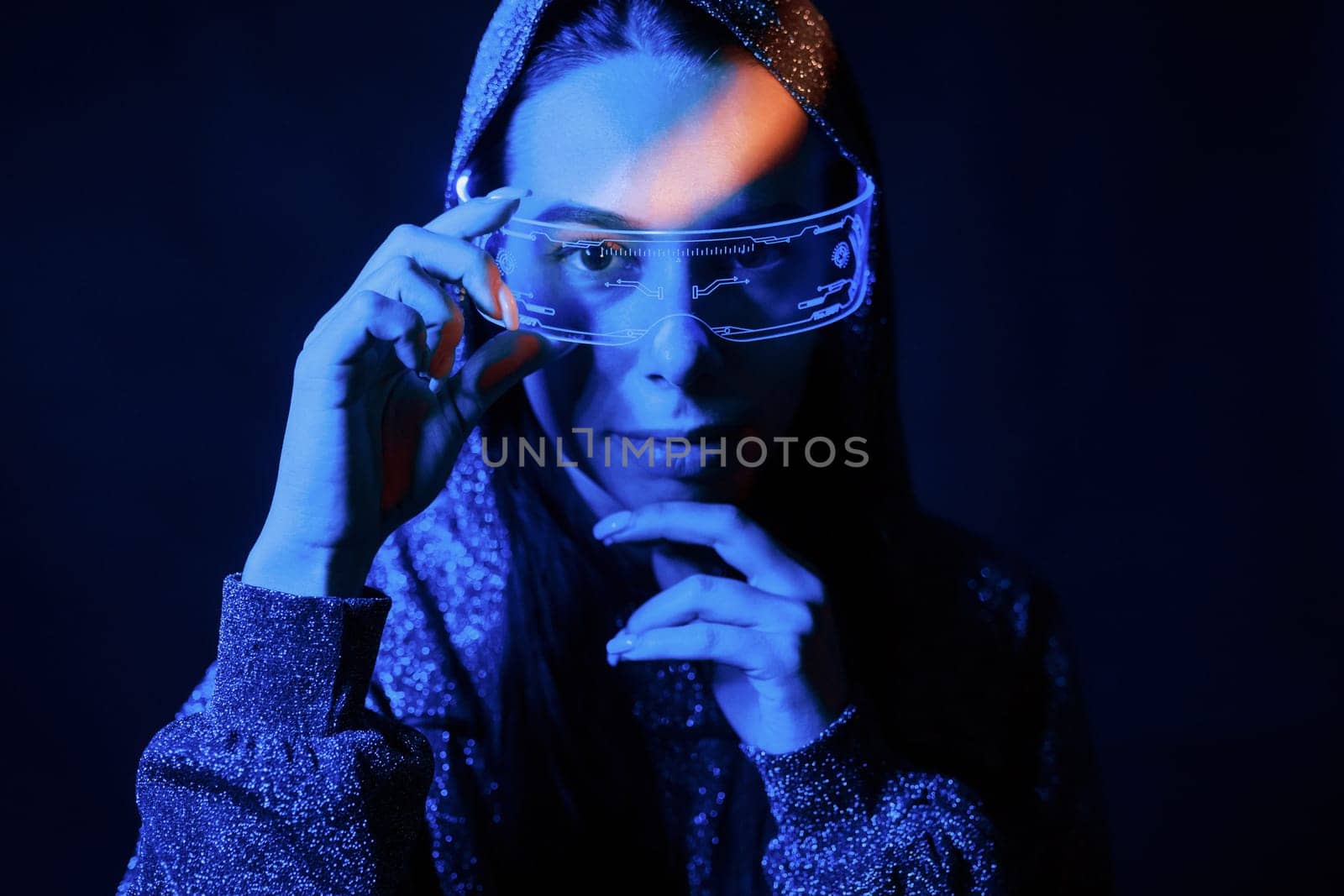 Portrait of young girl that is in eyeglasses in blue neon lighting.