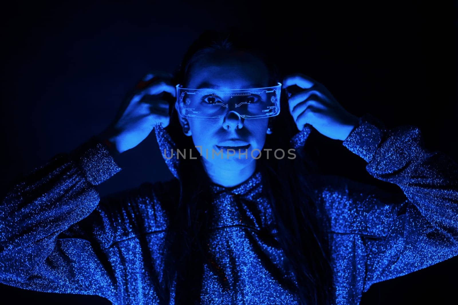 Portrait of young girl that is in eyeglasses in blue neon lighting.