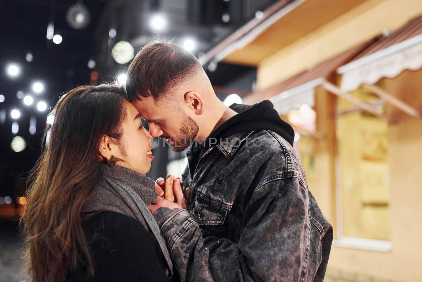 Embracing each other. Happy multiracial couple together outdoors in the city celebrating New year.