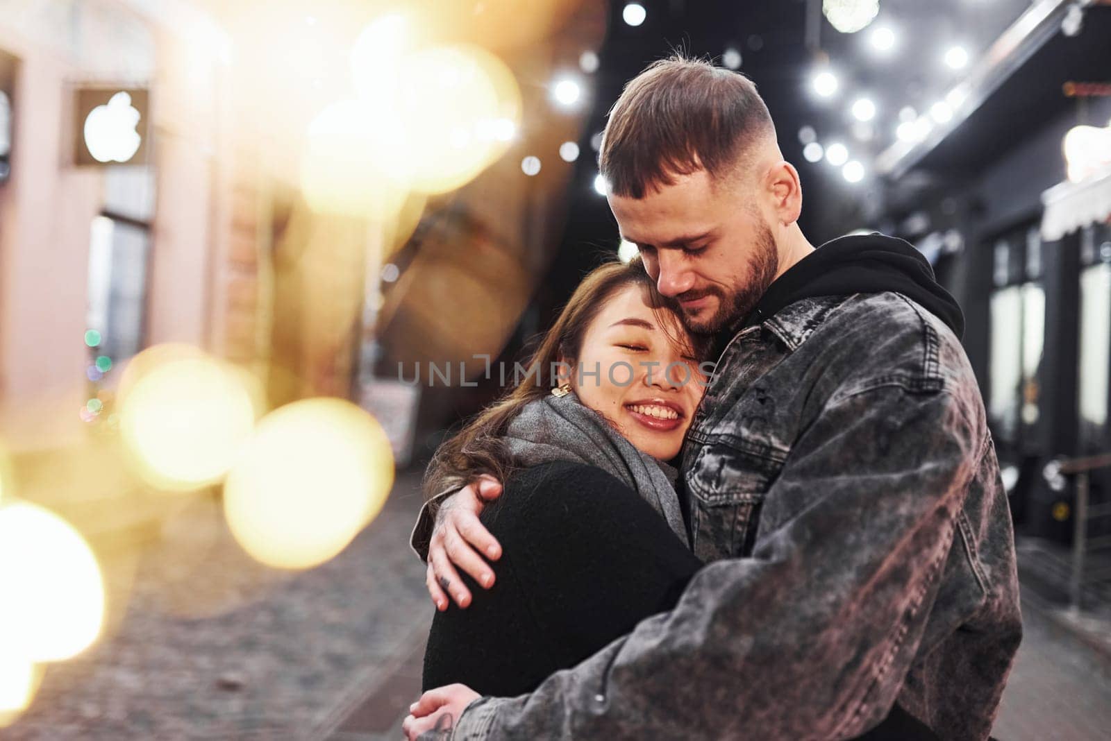 Embracing each other. Happy multiracial couple together outdoors in the city celebrating New year.
