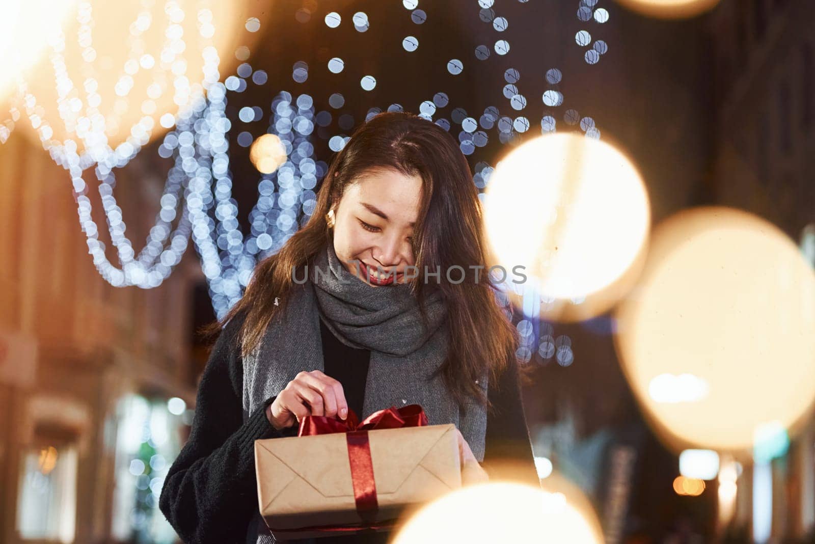 With gift box. Cute and happy asian young woman outdoors in the city celebrates New year.