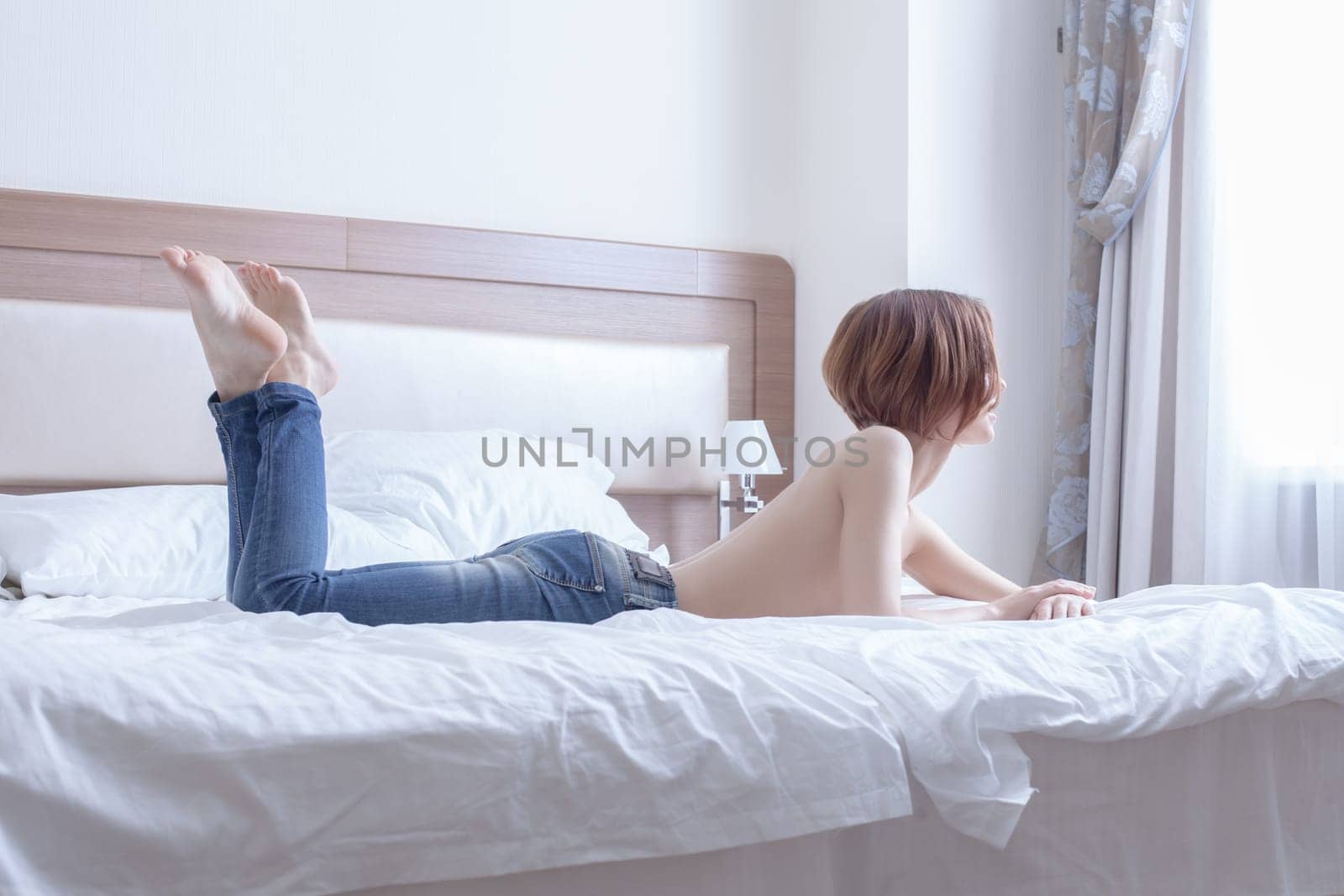 Beauty woman topless lay on bed look at window of morning bedroom