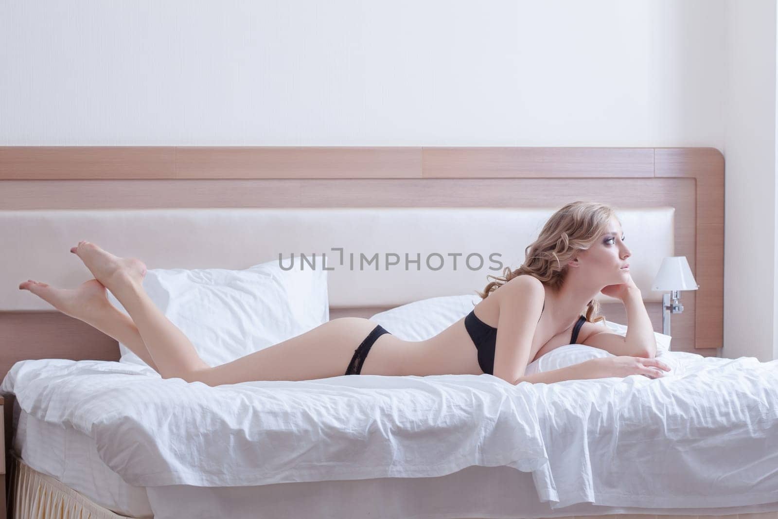 Full length portrait of Pretty blonde woman in black lingerie posing on bed