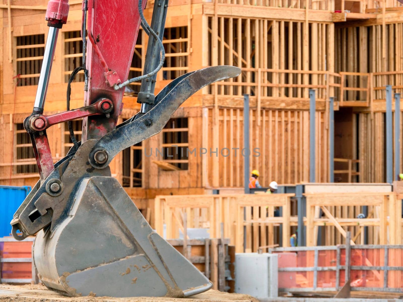 Iron excavator bucket on low-rise building construction background