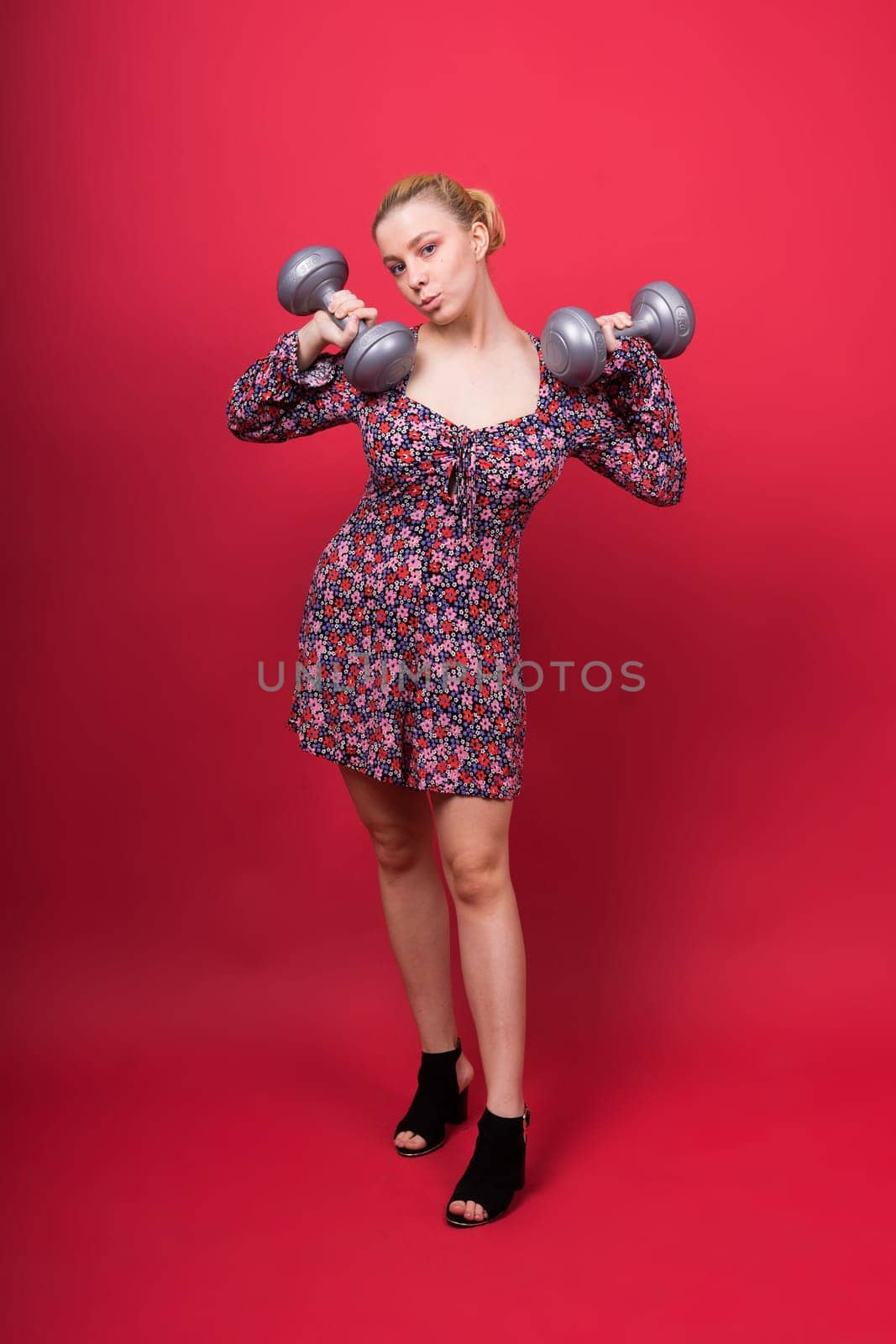 Smiling young plump fitness sporty seductive woman working out doing exercise with dumbbells by Zelenin