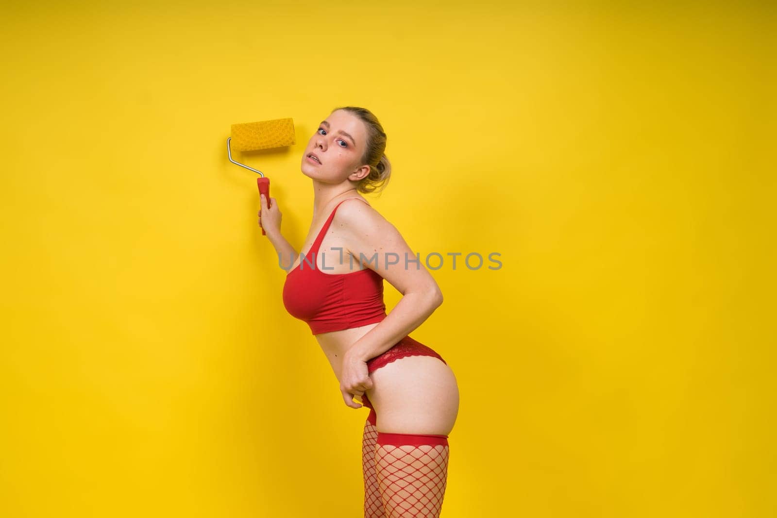 Young classic pin-up woman painting wall with a paint roller
