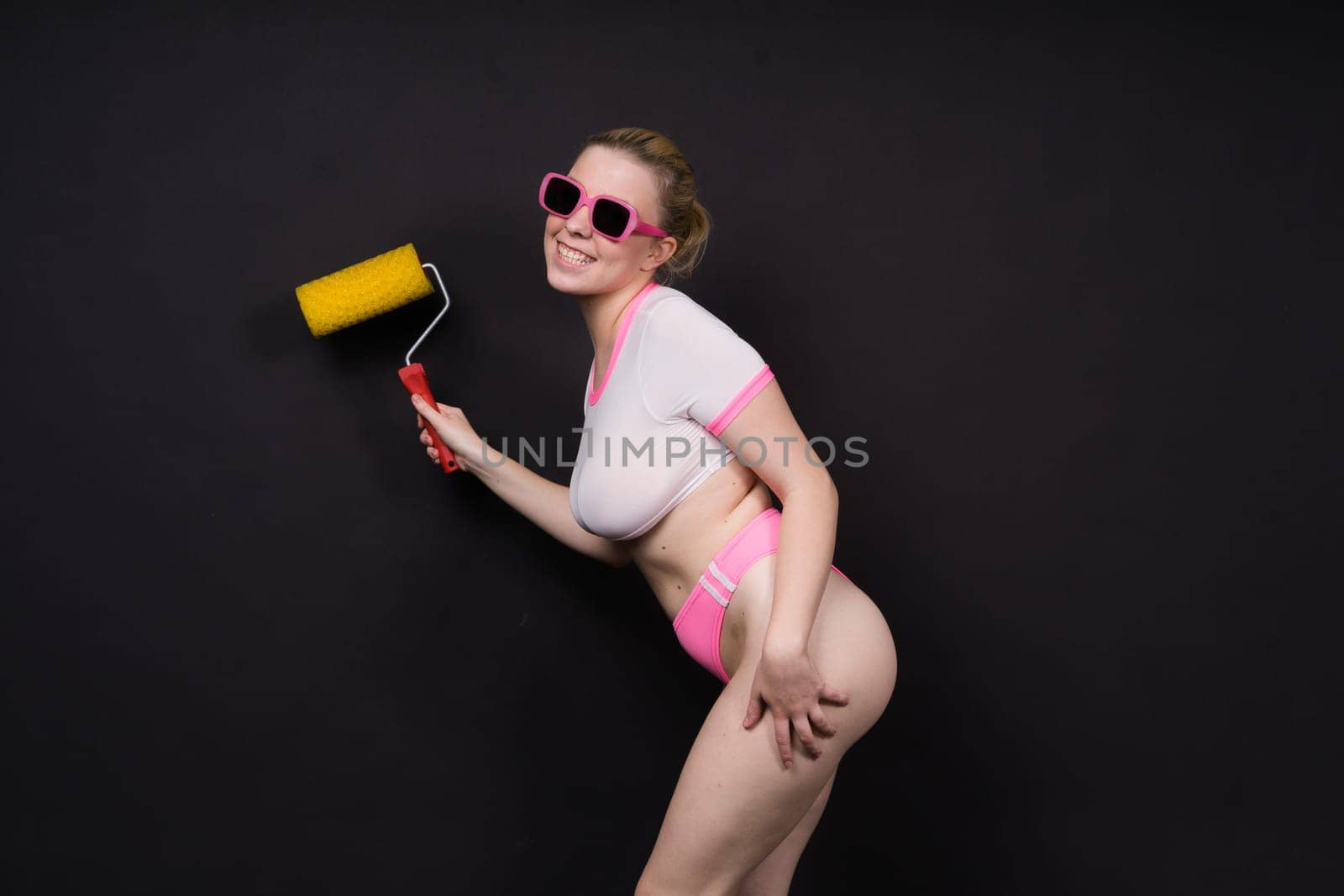 Young classic pin-up woman painting wall with paint roller by Zelenin