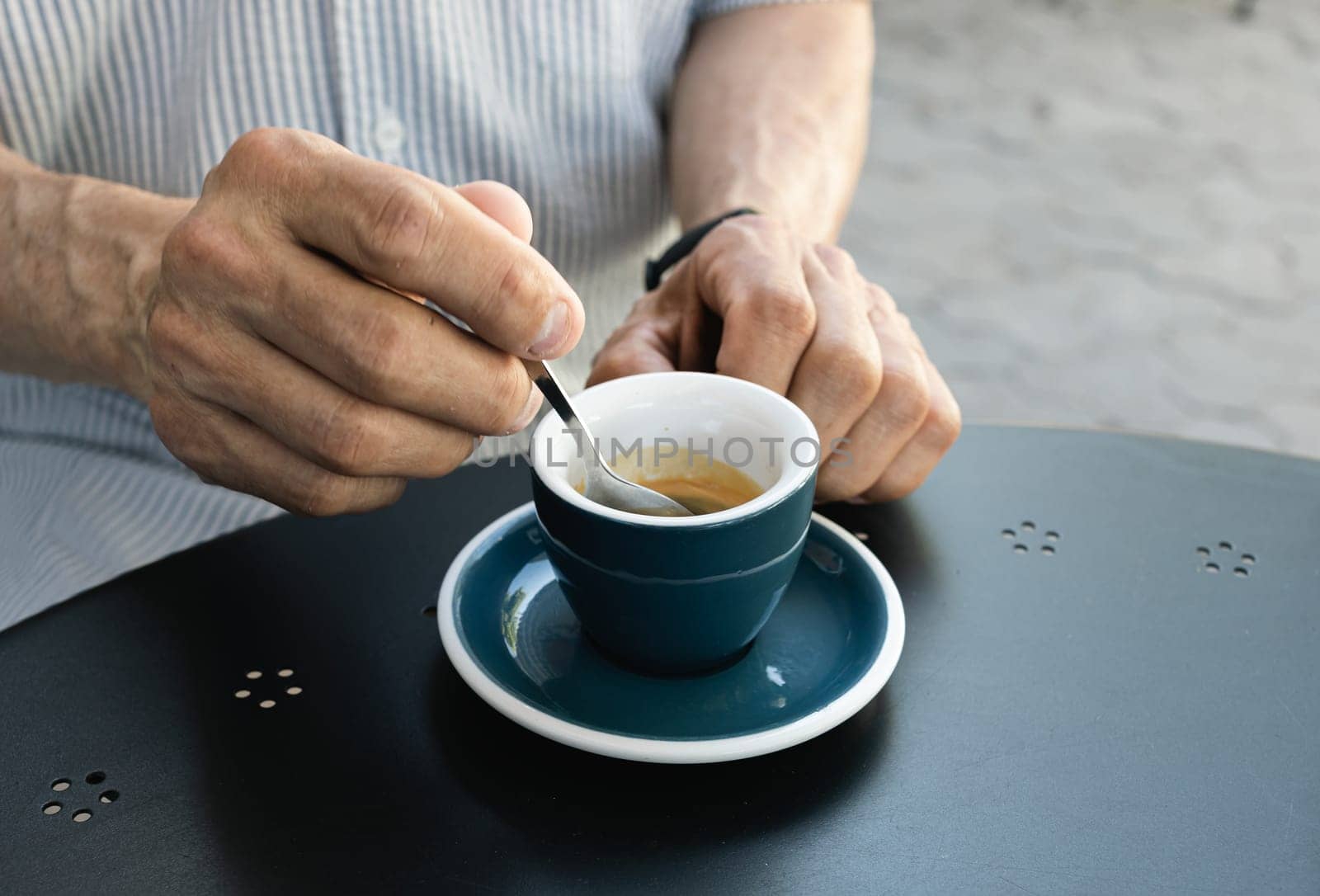 Lifestyle concept. An elderly man drinking espresso coffee at an outdoor cafe in the early hours of the morning before work.
