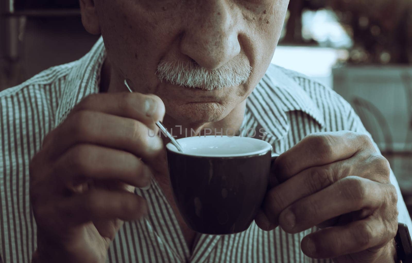 Lifestyle concept. An elderly man drinking espresso coffee at an outdoor cafe in the early hours of the morning before work.
