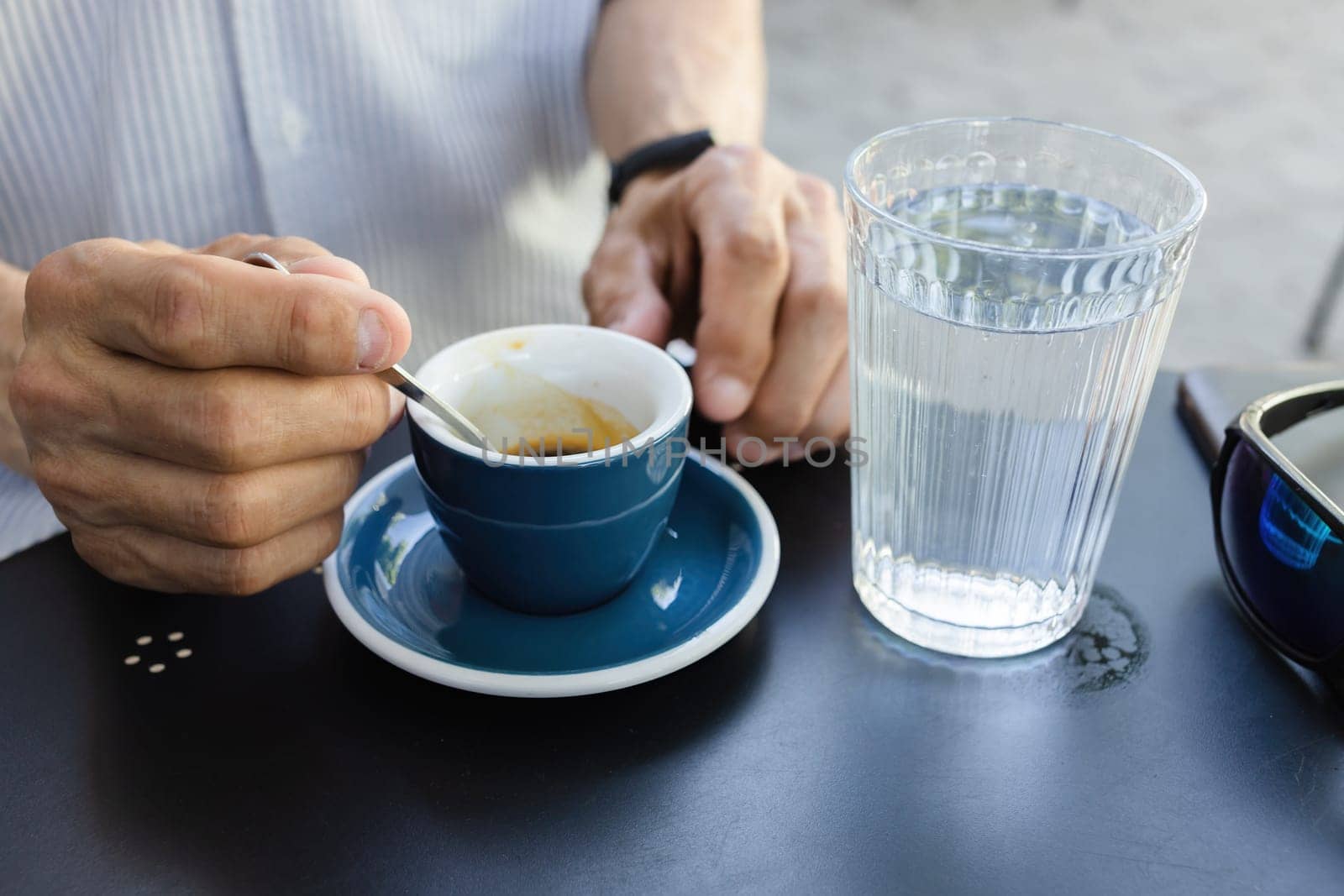 Lifestyle concept. An elderly man drinking espresso coffee at an outdoor cafe in the early hours of the morning before work.
