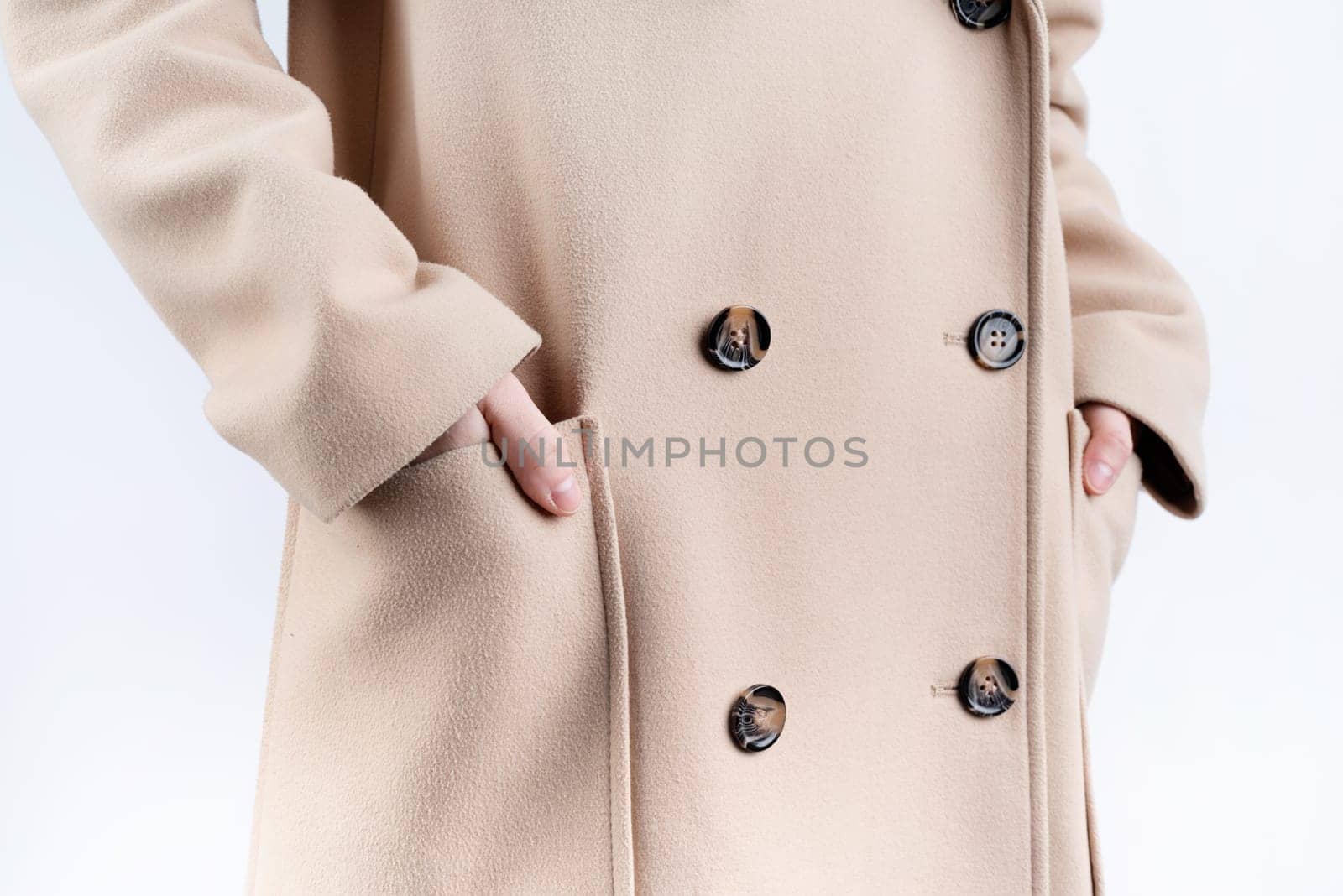 closeup woman in beige coat choosing outfit dressing on white background. Selection of a wardrobe, stylist, shopping.