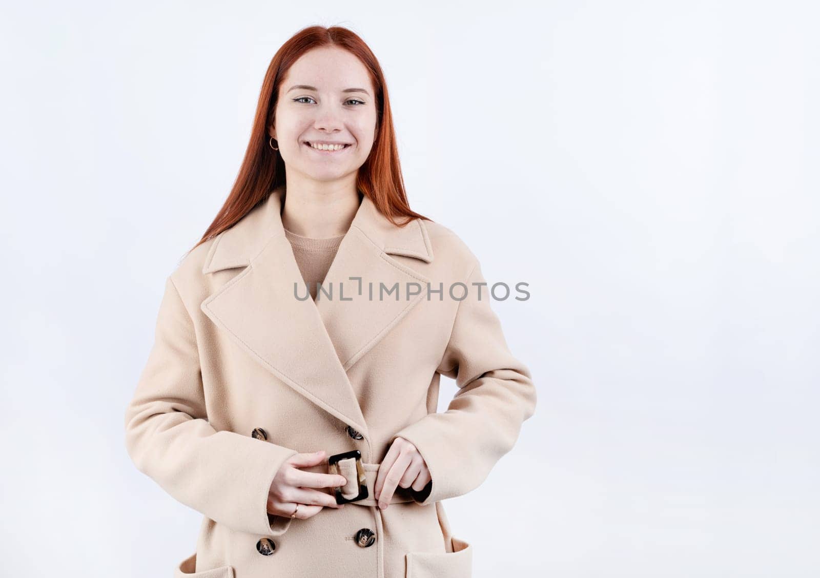 young beautiful woman wearing beige pastel coat in white background by Desperada