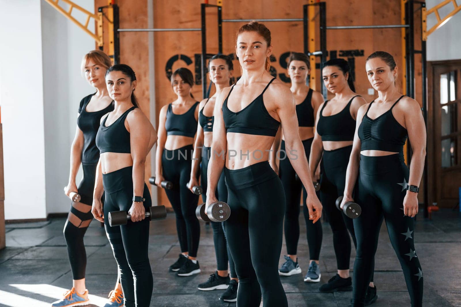 Posing for a camera. Group of young sportive people have crossfit day indoors in gym.