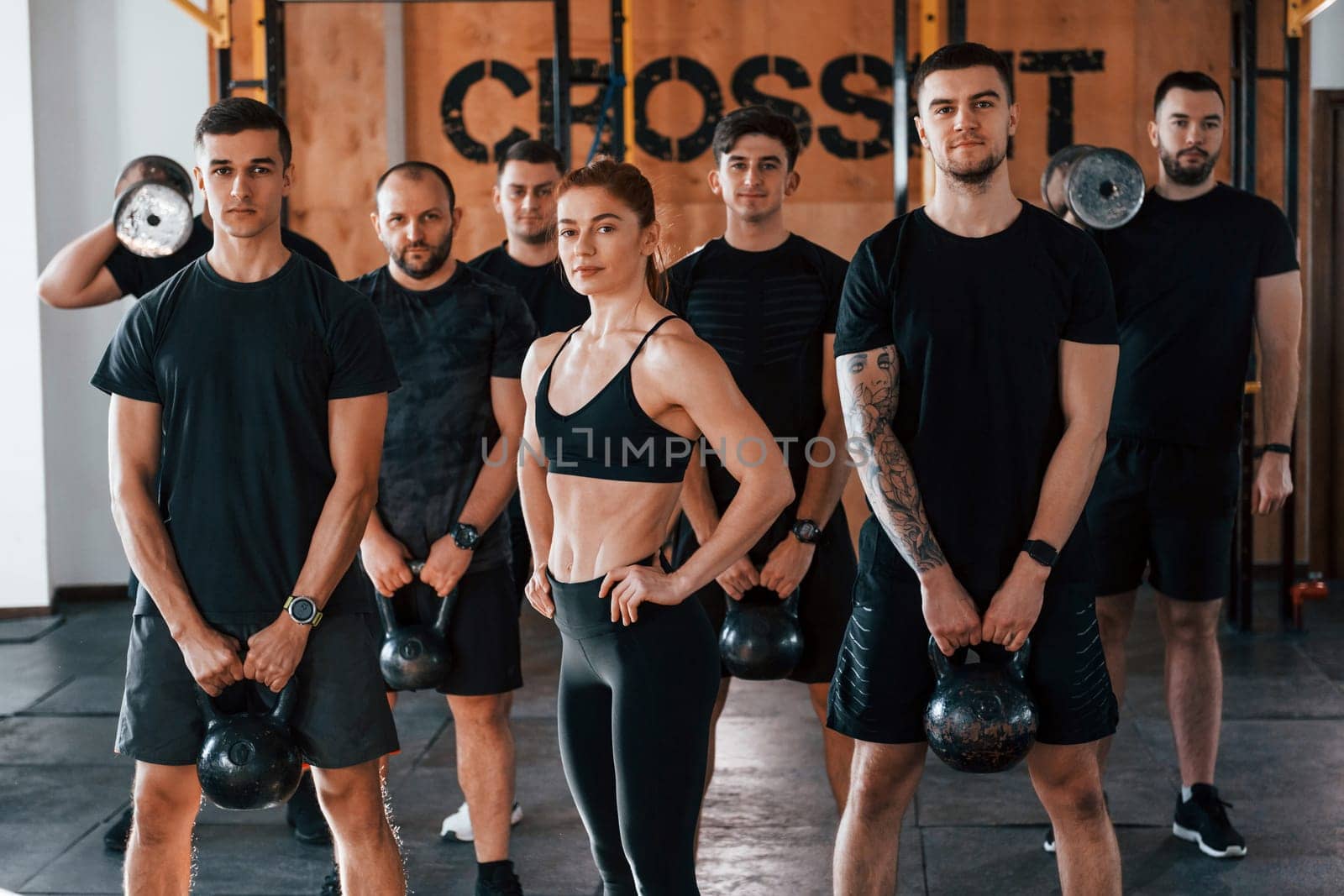 Posing for a camera. Group of young sportive people have crossfit day indoors in gym.