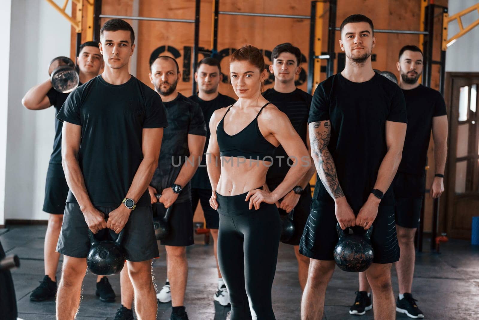 Posing for a camera. Group of young sportive people have crossfit day indoors in gym.