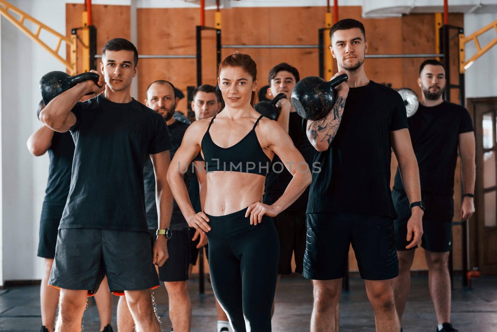 Posing for a camera. Group of young sportive people have crossfit day indoors in gym.