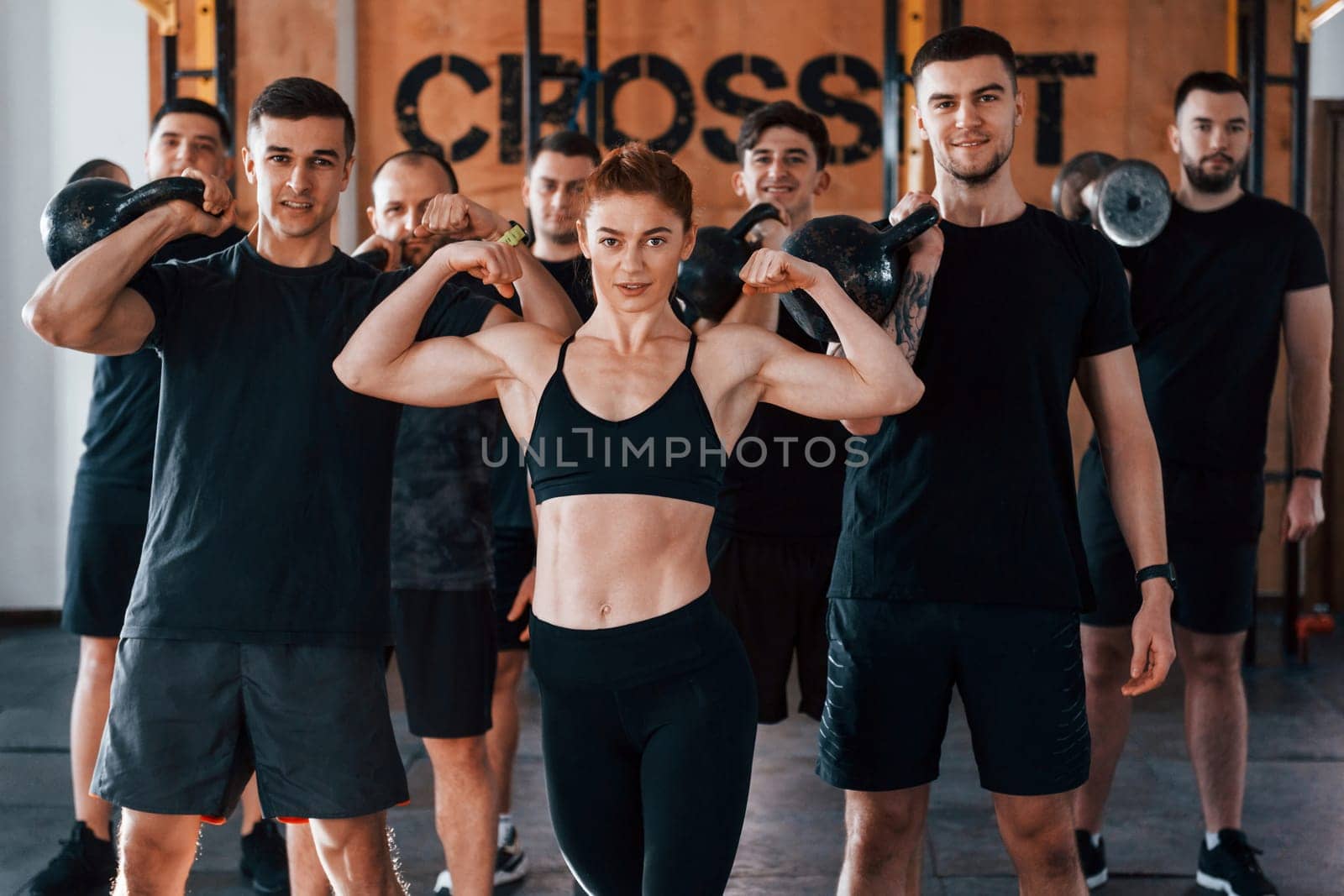 Posing for a camera. Group of young sportive people have crossfit day indoors in gym.