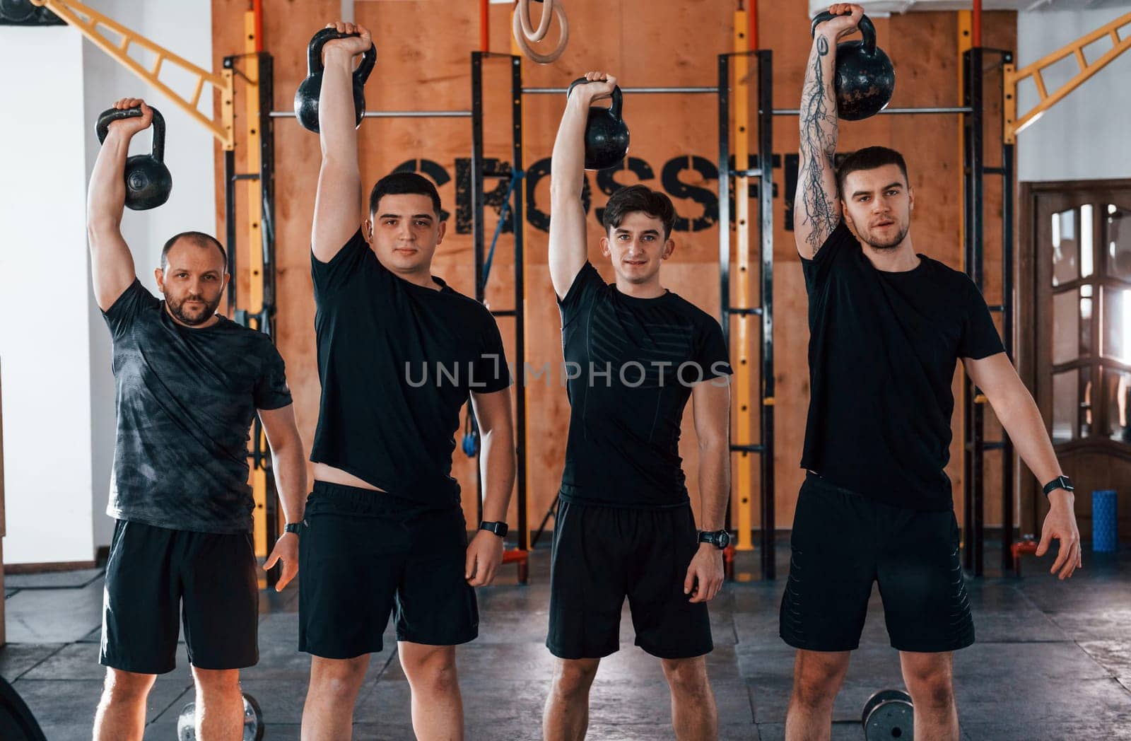 Lifting of heavy weights. Group of young sportive people have crossfit day indoors in gym.