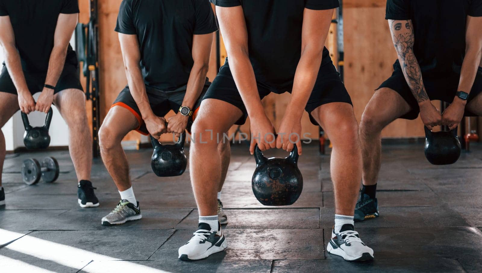 Lifting of heavy weights. Group of young sportive people have crossfit day indoors in gym.
