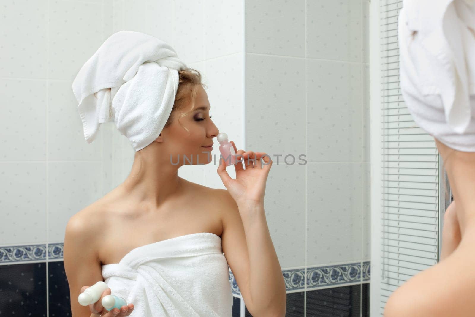 Young woman in towel relax in bathroom and smell perfume