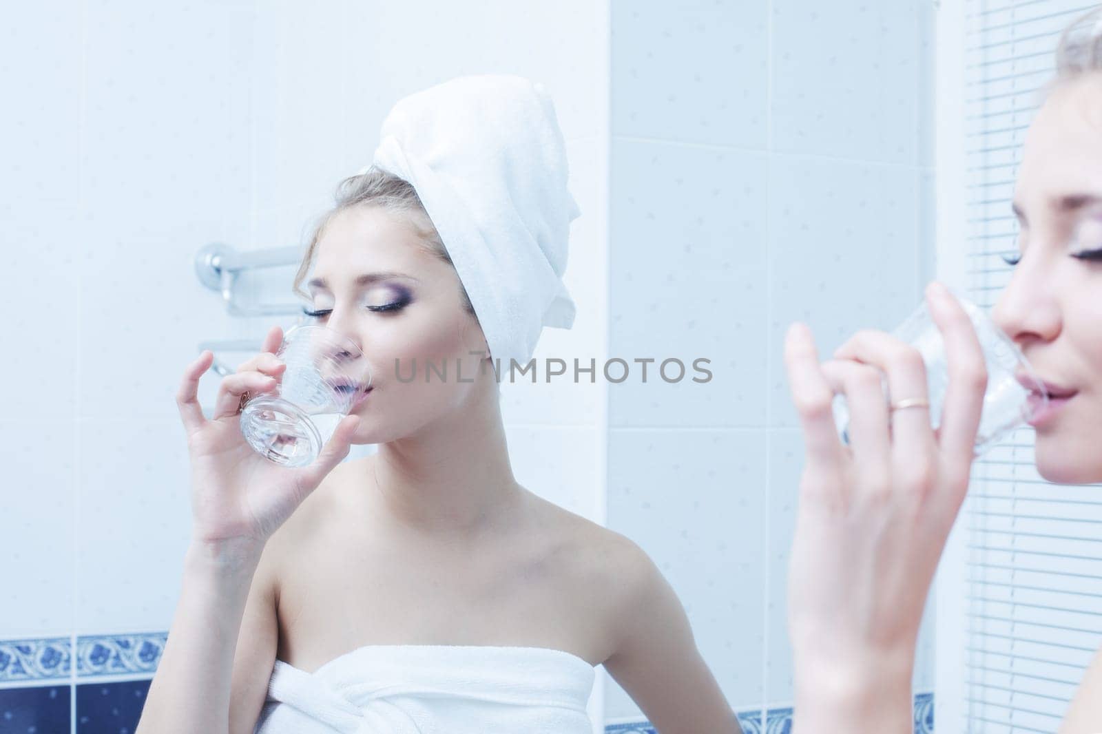 Young woman with glass of water in bathroom