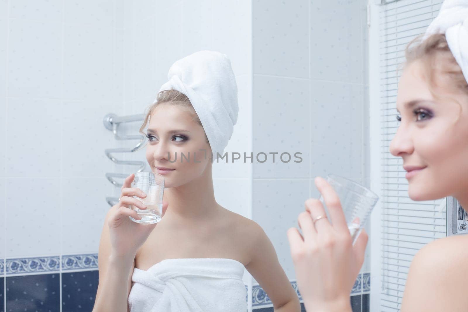 Portrait of woman with glass in bathroom