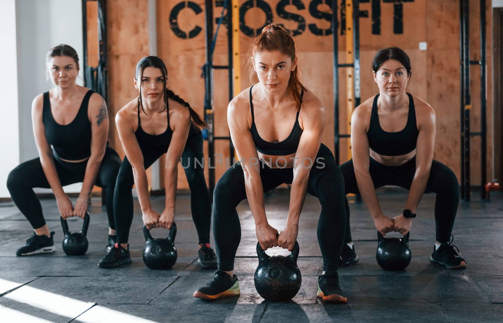 Lifting of heavy weights. Group of young sportive people have crossfit day indoors in gym.