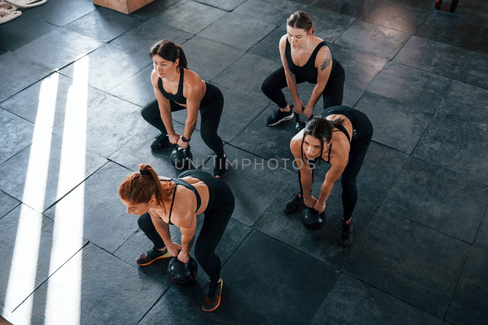 Lifting of heavy weights. Group of young sportive people have crossfit day indoors in gym.