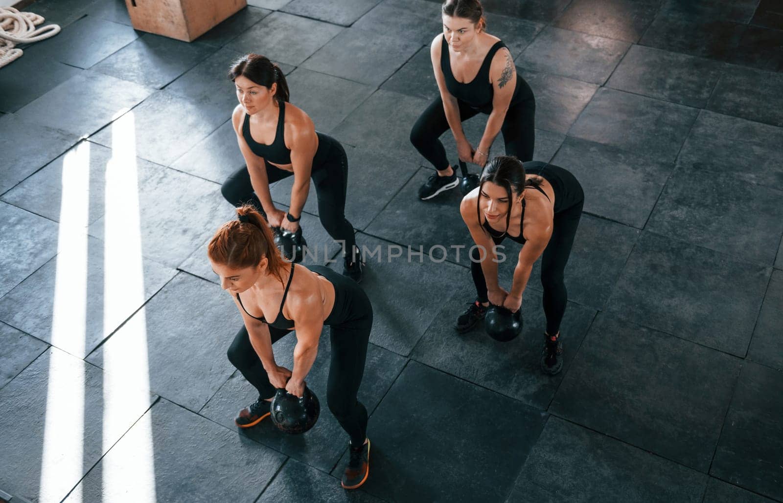 Lifting of heavy weights. Group of young sportive people have crossfit day indoors in gym.