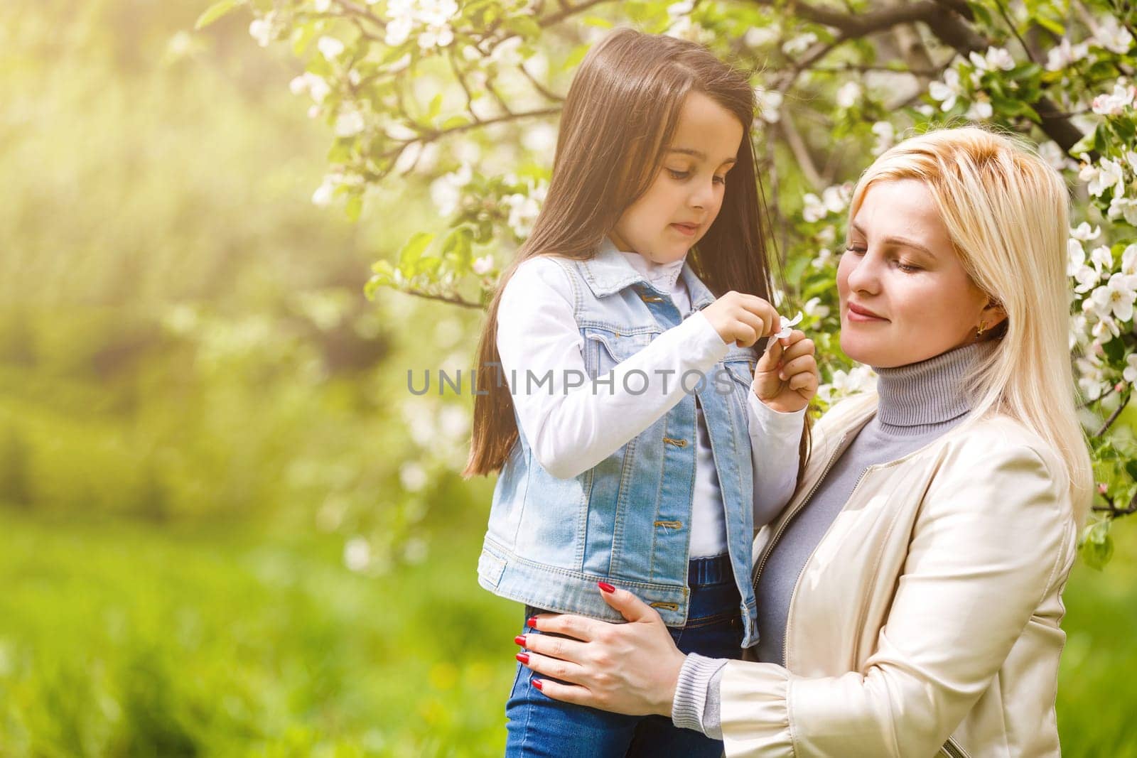 Happy woman and child in the blooming spring garden. Mothers day holiday concept. by Andelov13