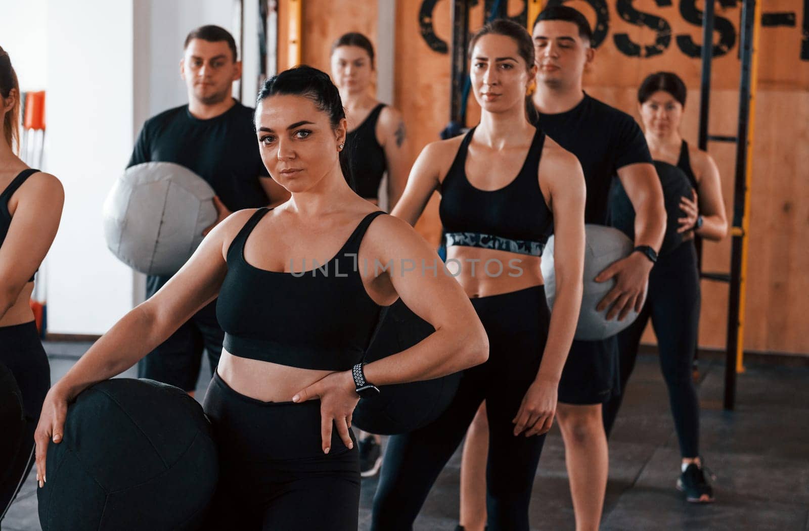 With fitness balls. Group of young sportive people have crossfit day indoors in gym.