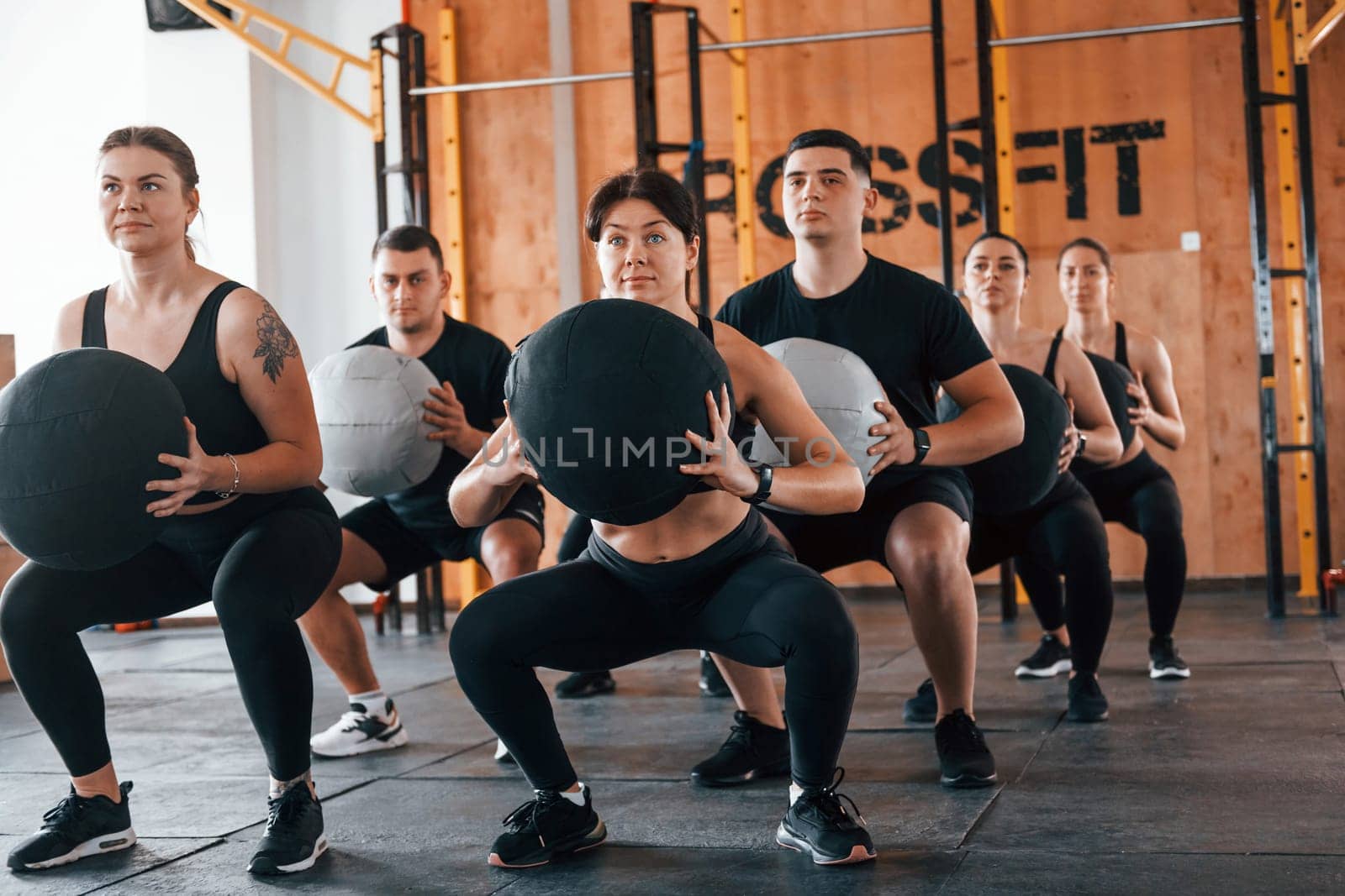 With fitness balls. Group of young sportive people have crossfit day indoors in gym.