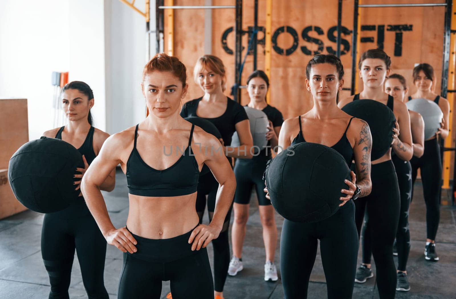 With fitness balls. Group of young sportive people have crossfit day indoors in gym.