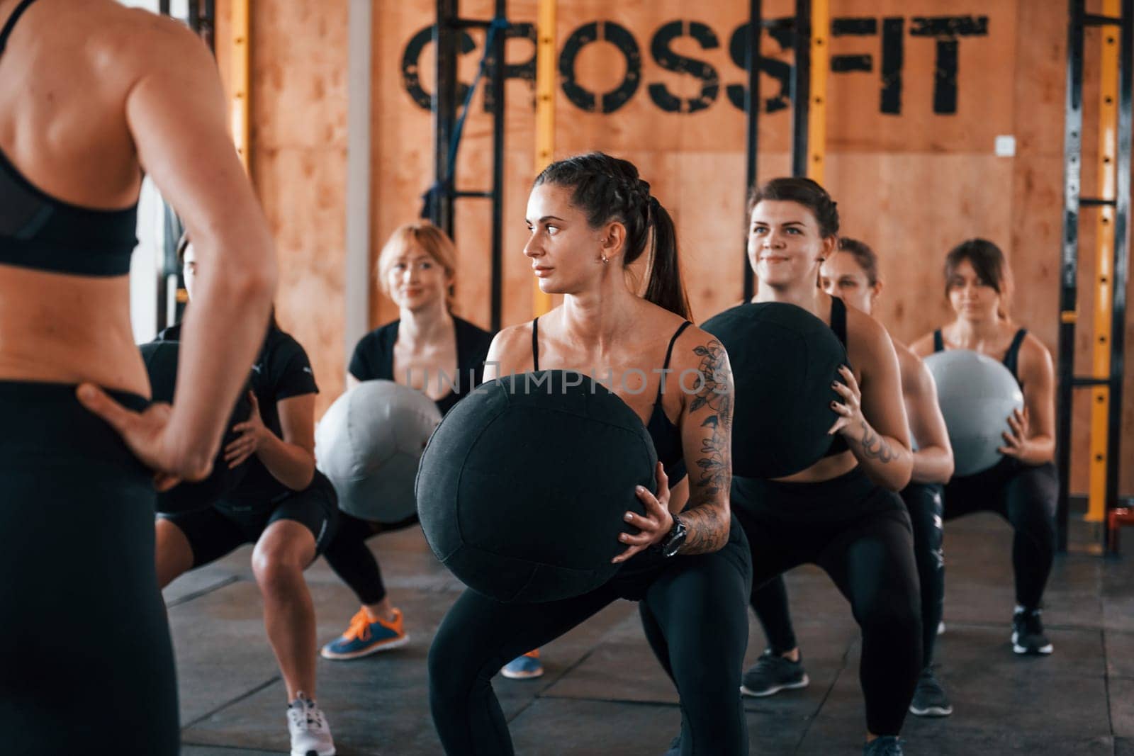 With fitness balls. Group of young sportive people have crossfit day indoors in gym.