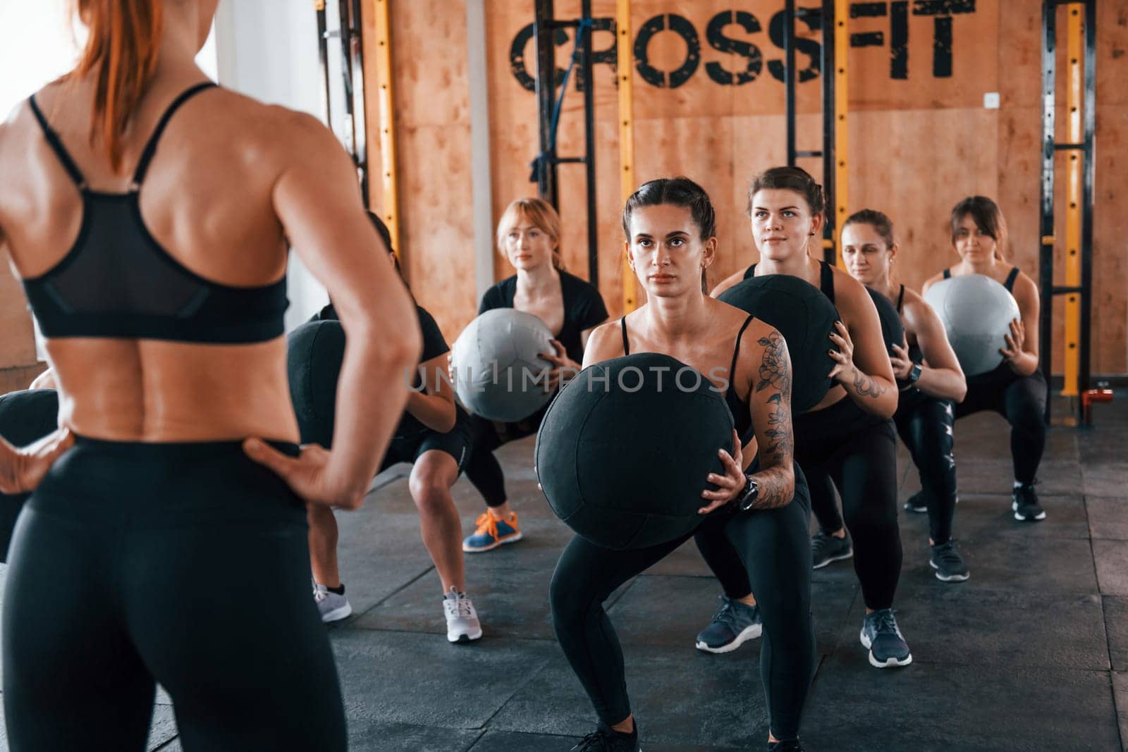 With fitness balls. Group of young sportive people have crossfit day indoors in gym.