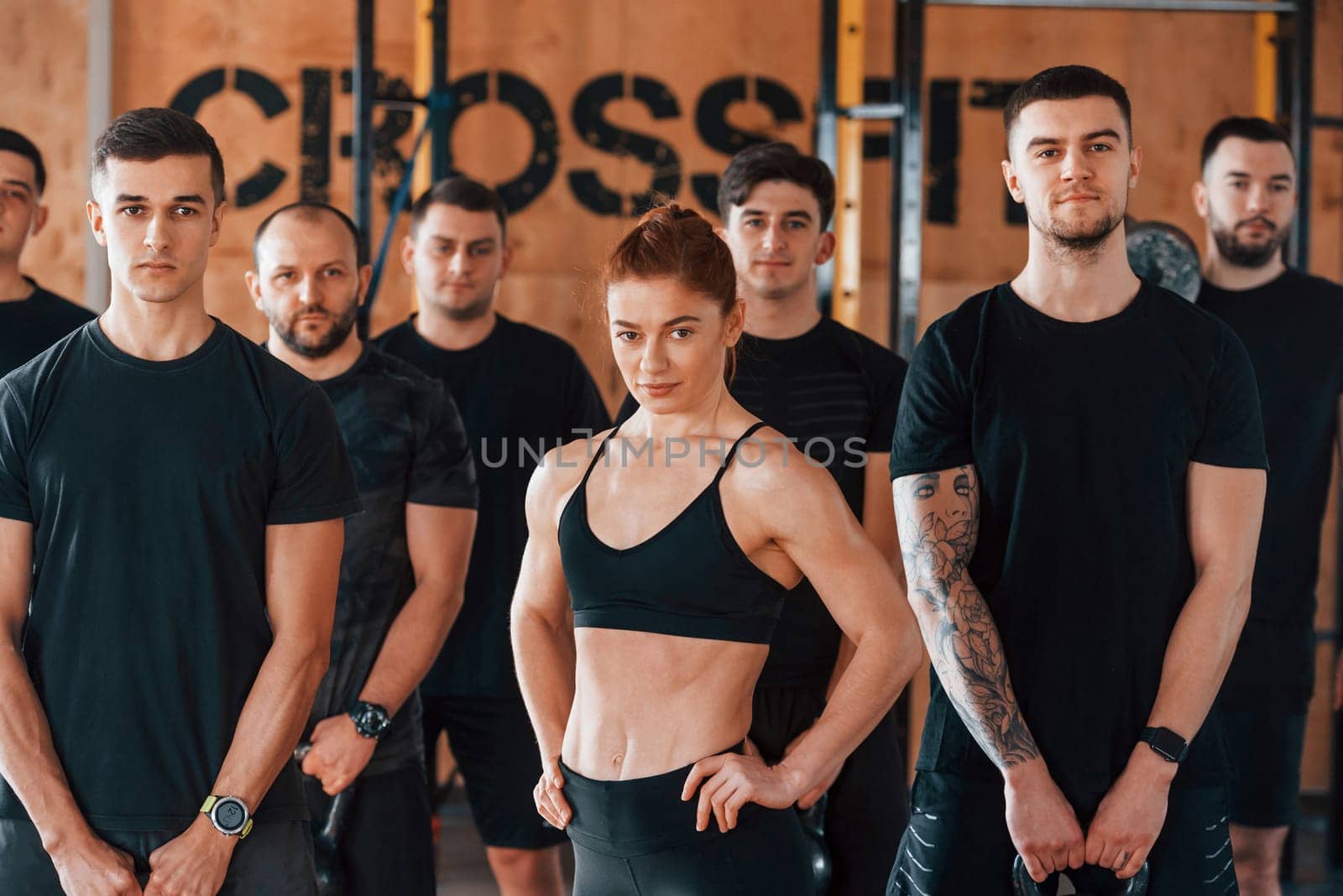 Posing for a camera. Group of young sportive people have crossfit day indoors in gym.