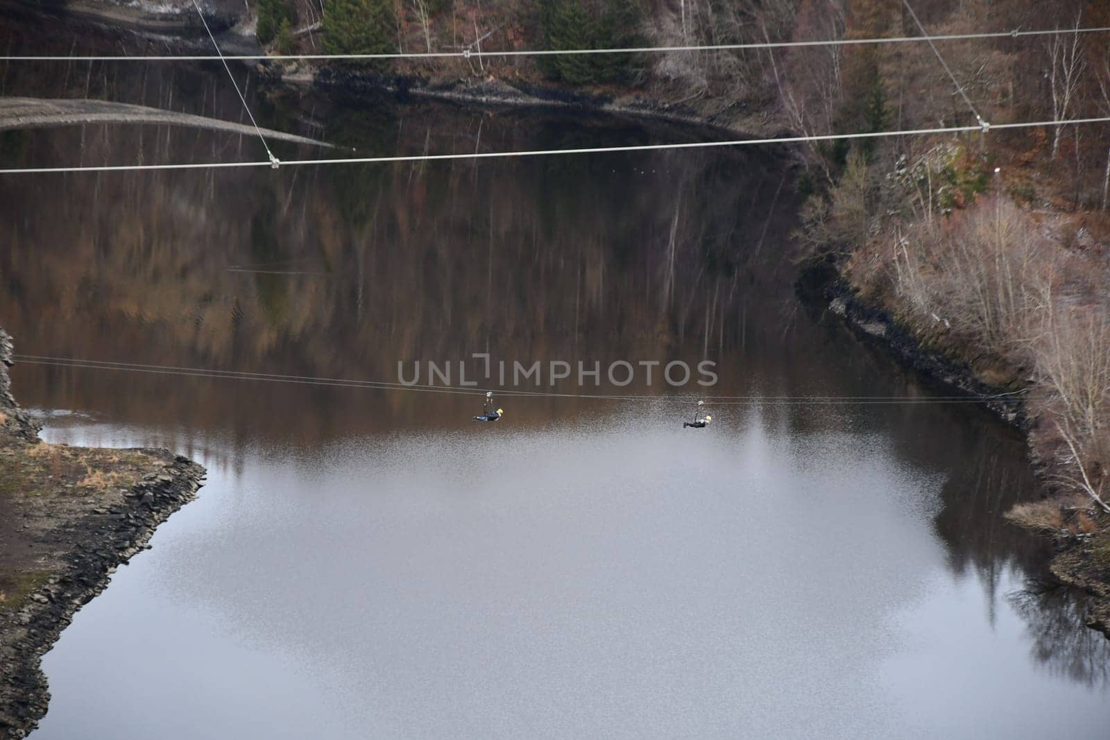 People on a giant zipline flying over the Rappbode reservoir near Elbingerode, Harz, Germany