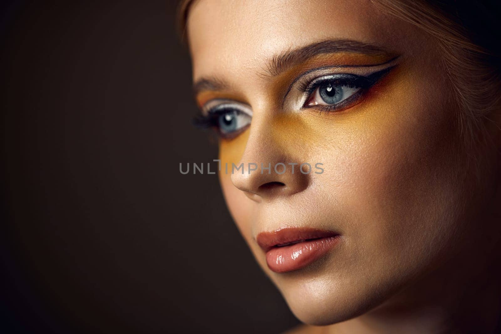 close-up portrait of beauty blonde model girl with fashionable creative make-up, bright eye line. Creative yellow eye makeup ideas.
