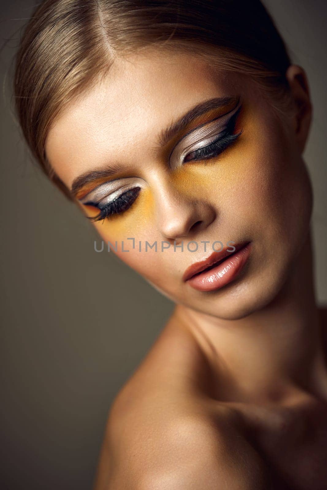 gorgeous blonde model girl with fashionable creative make-up, bright eye line. Creative yellow eye makeup ideas.