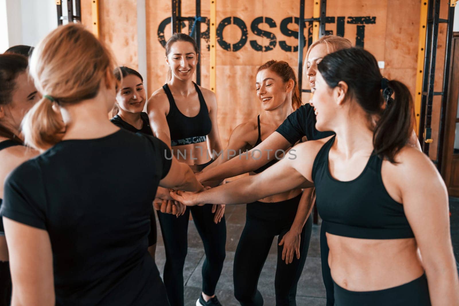Taking a break. Group of young sportive people have crossfit day indoors in gym.