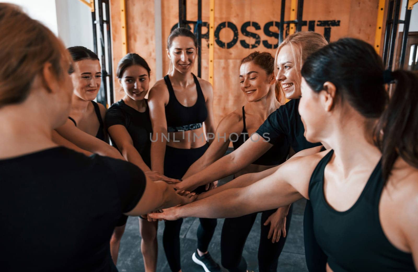 Taking a break. Group of young sportive people have crossfit day indoors in gym.