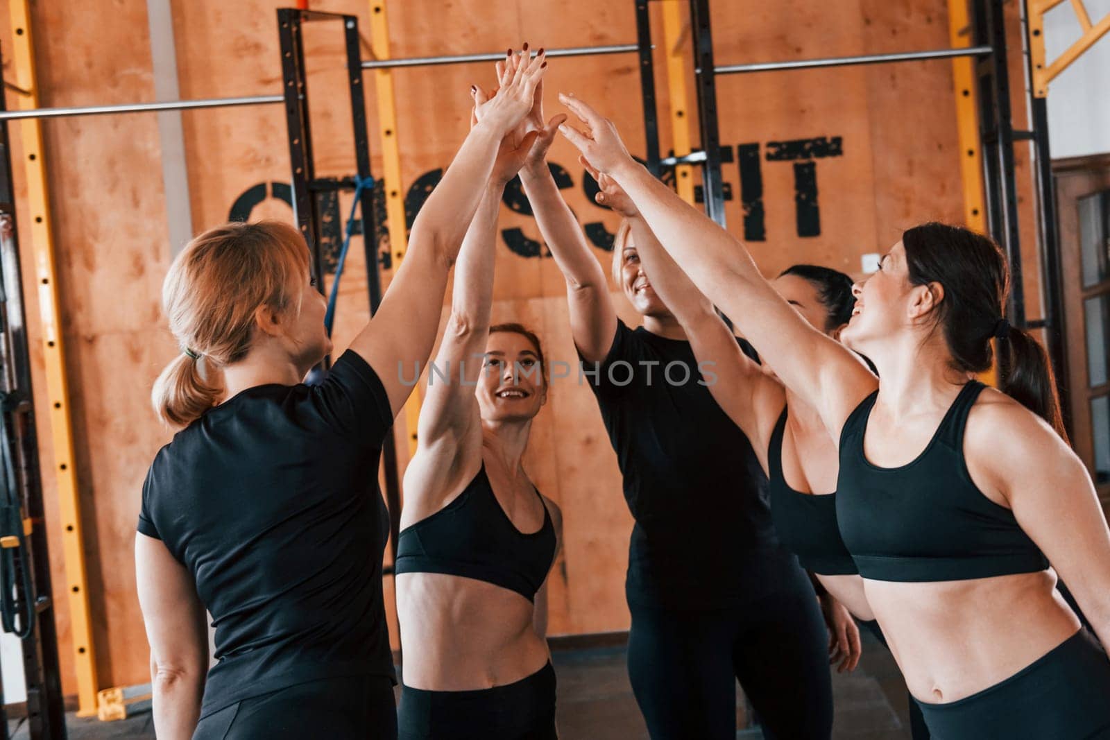 Taking a break. Group of young sportive people have crossfit day indoors in gym.