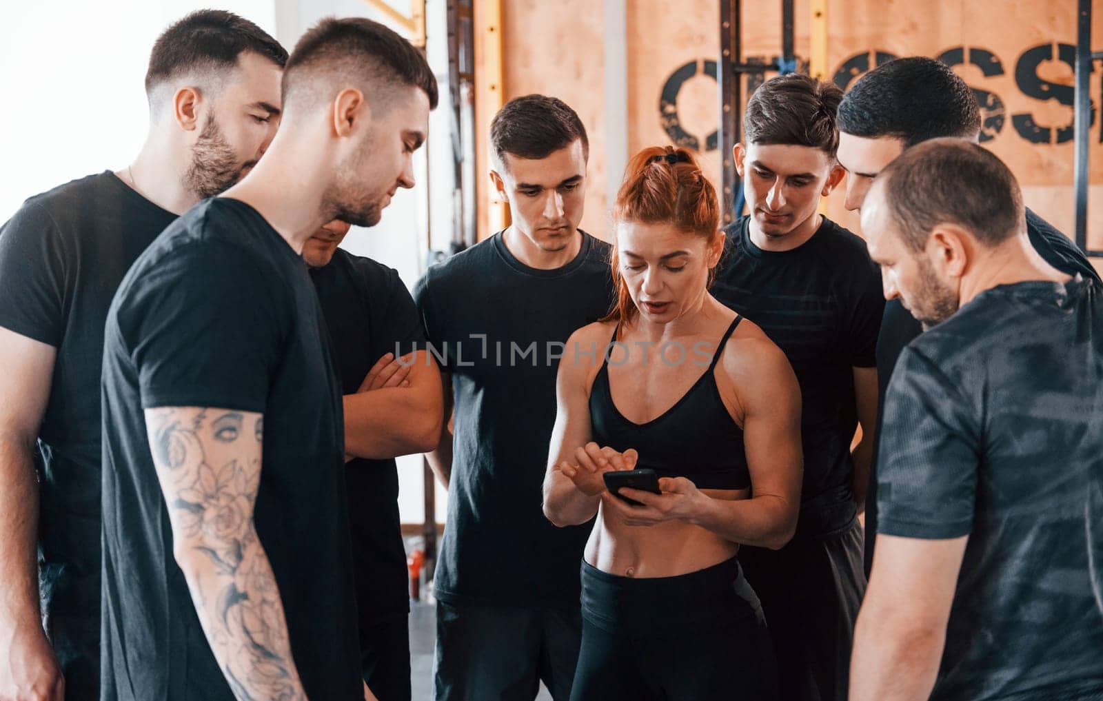 Taking a break. Group of young sportive people have crossfit day indoors in gym.