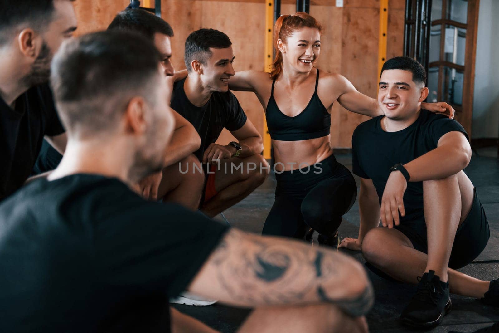 Taking a break. Group of young sportive people have crossfit day indoors in gym.