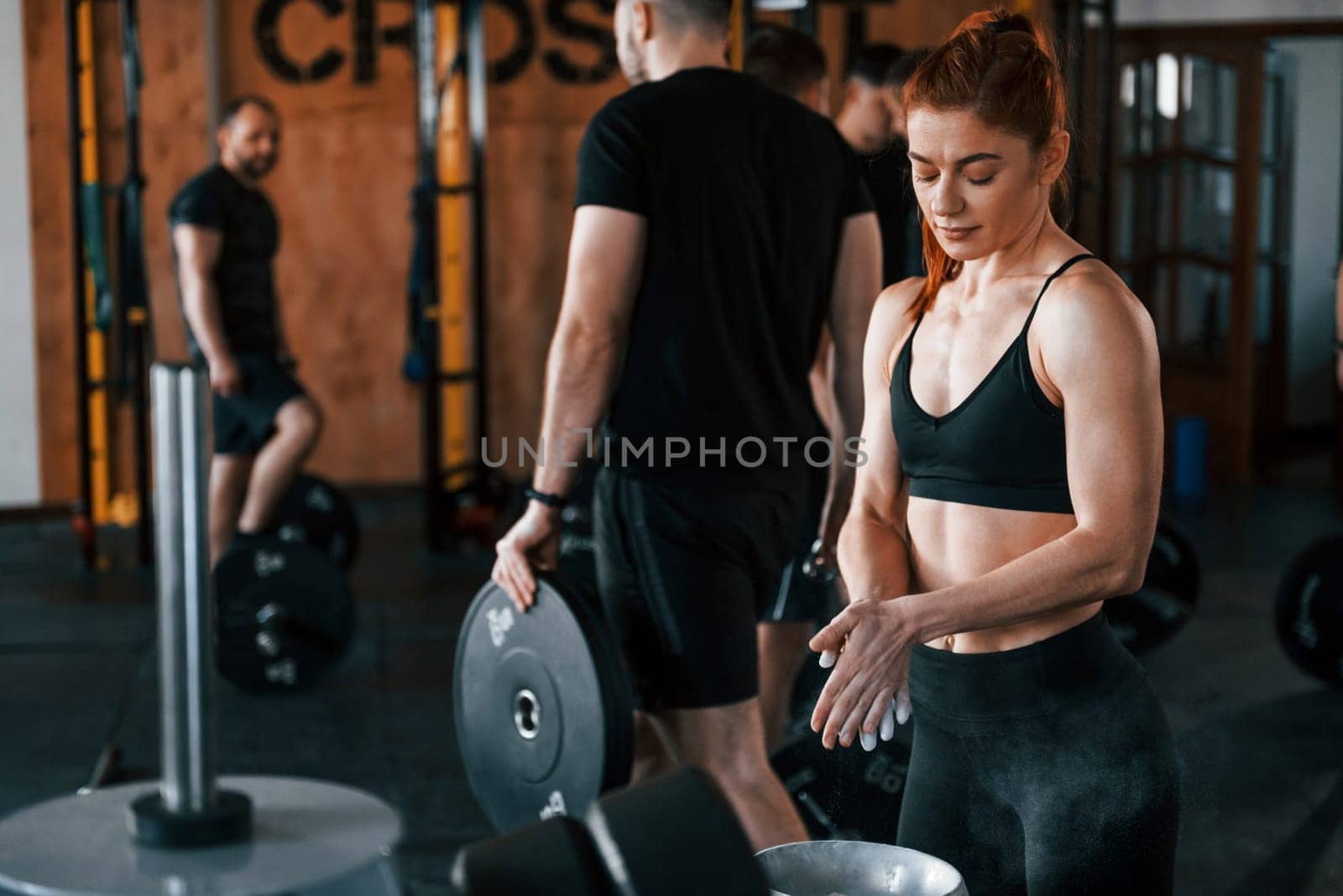 Group of young sportive people have crossfit day indoors in gym.