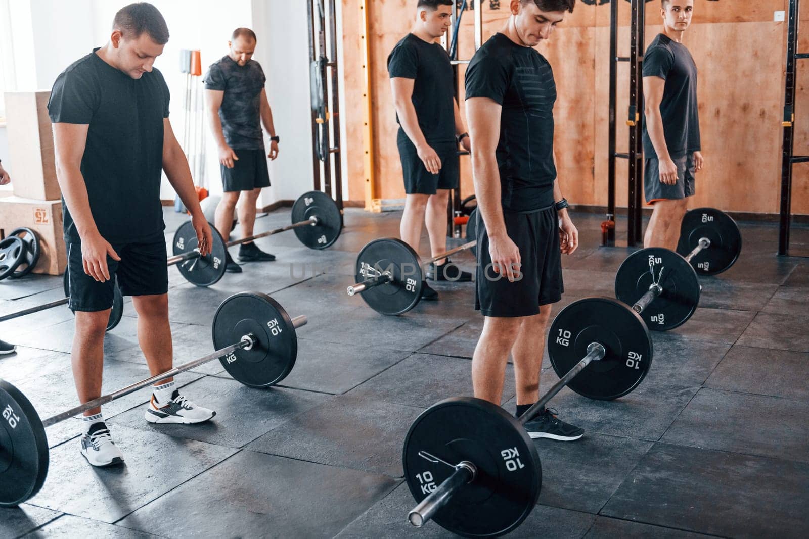 Group of young sportive people have crossfit day indoors in gym.