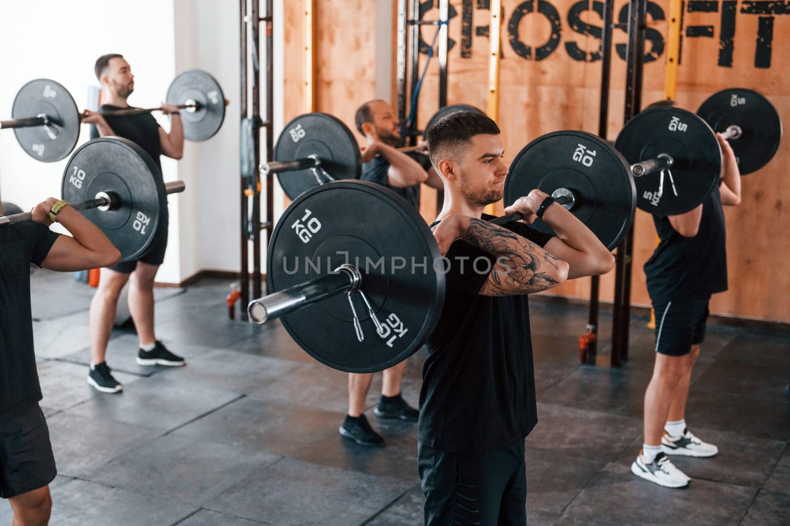 Group of young sportive people have crossfit day indoors in gym.