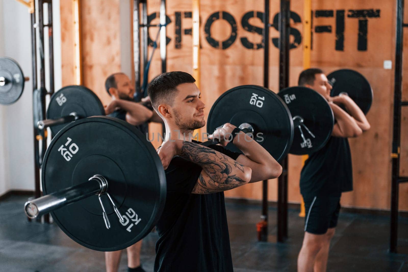 Group of young sportive people have crossfit day indoors in gym.