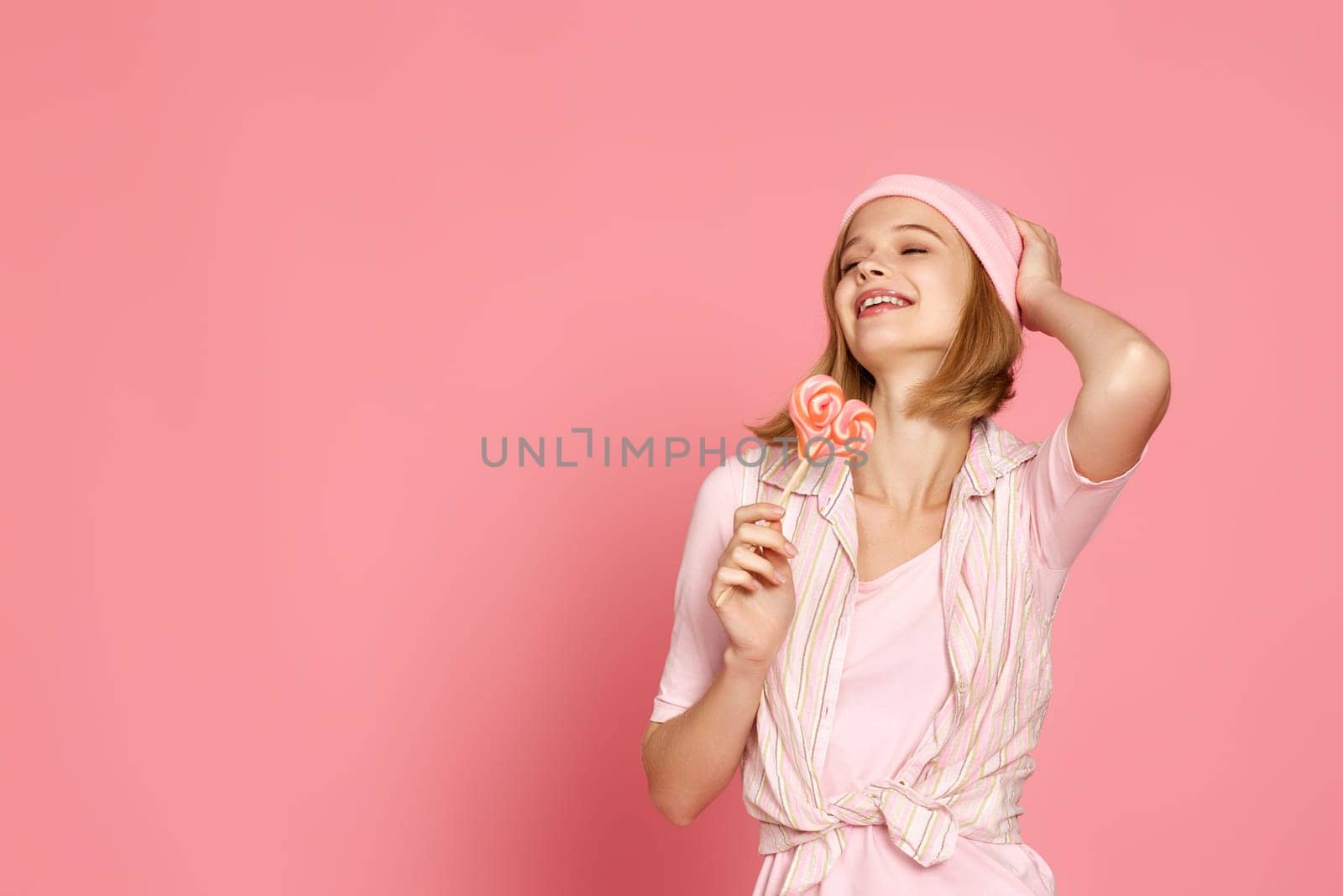 Lovely blonde woman holding candy on pink background. copy space